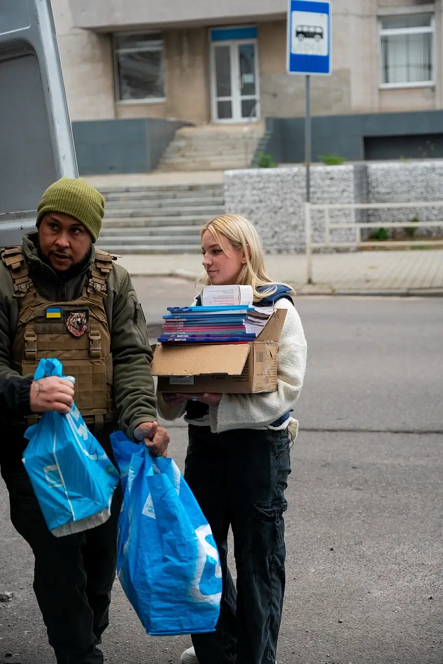 Kelsie Kimberlin accompanied by a soldier is delivering humanitarian aid Kelsie Kimberlin accompanied by a soldier is delivering humanitarian aid
