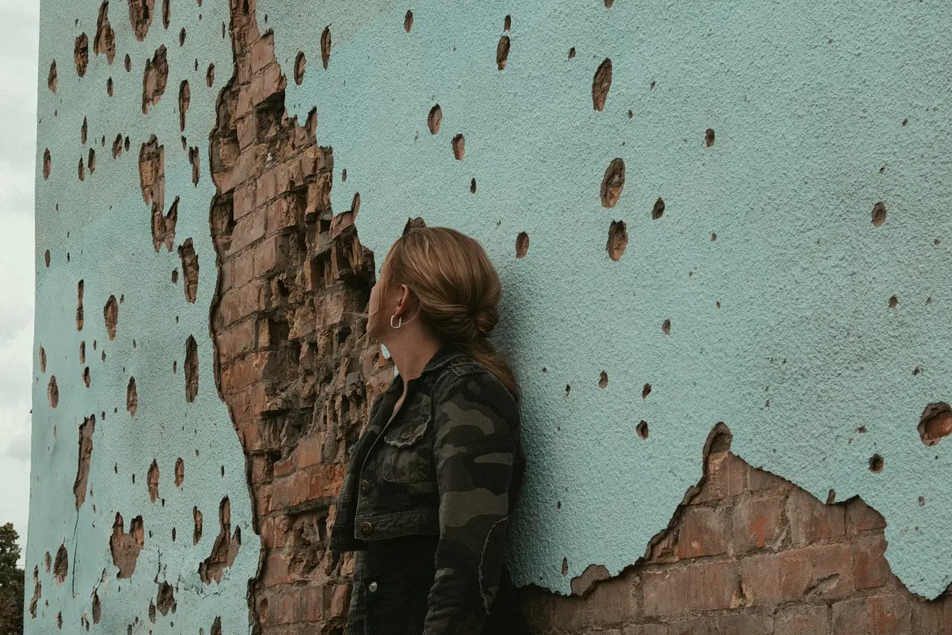 Kelsie Kimberlin sits against a wall pockmarked with shell holes Kelsie Kimberlin sits against a wall pockmarked with shell holes