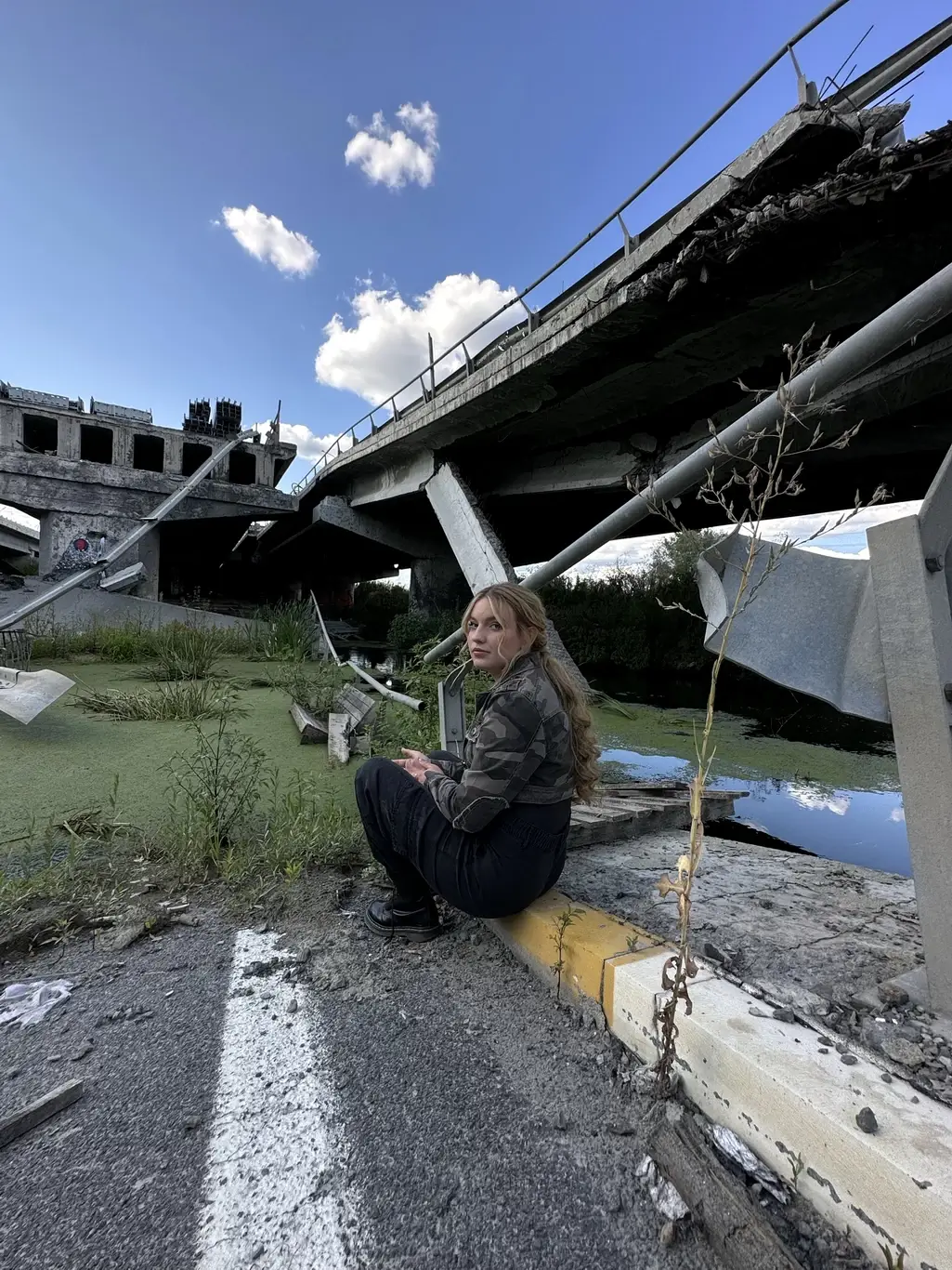 Kelsie Kimberlin sits near a destroyed bridge